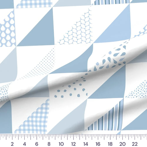 Blue half-square triangle cheater quilt fabric by the yard with 6 inch blocks, draped quilting cotton with a ruler showing true scale