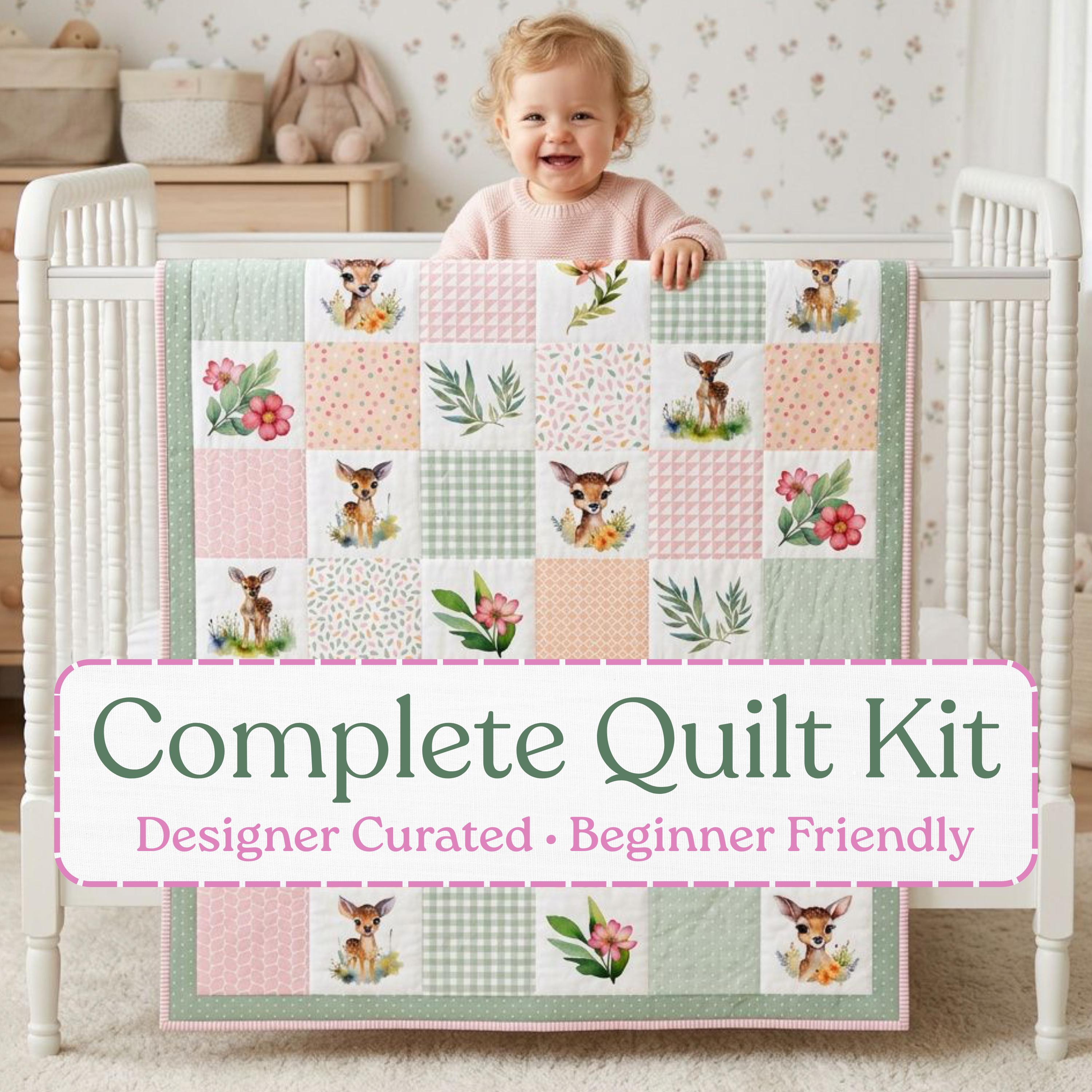 Meadow Fawn baby quilt kit – finished quilt with watercolor deer, florals and sage and blush patchwork, held by a smiling baby