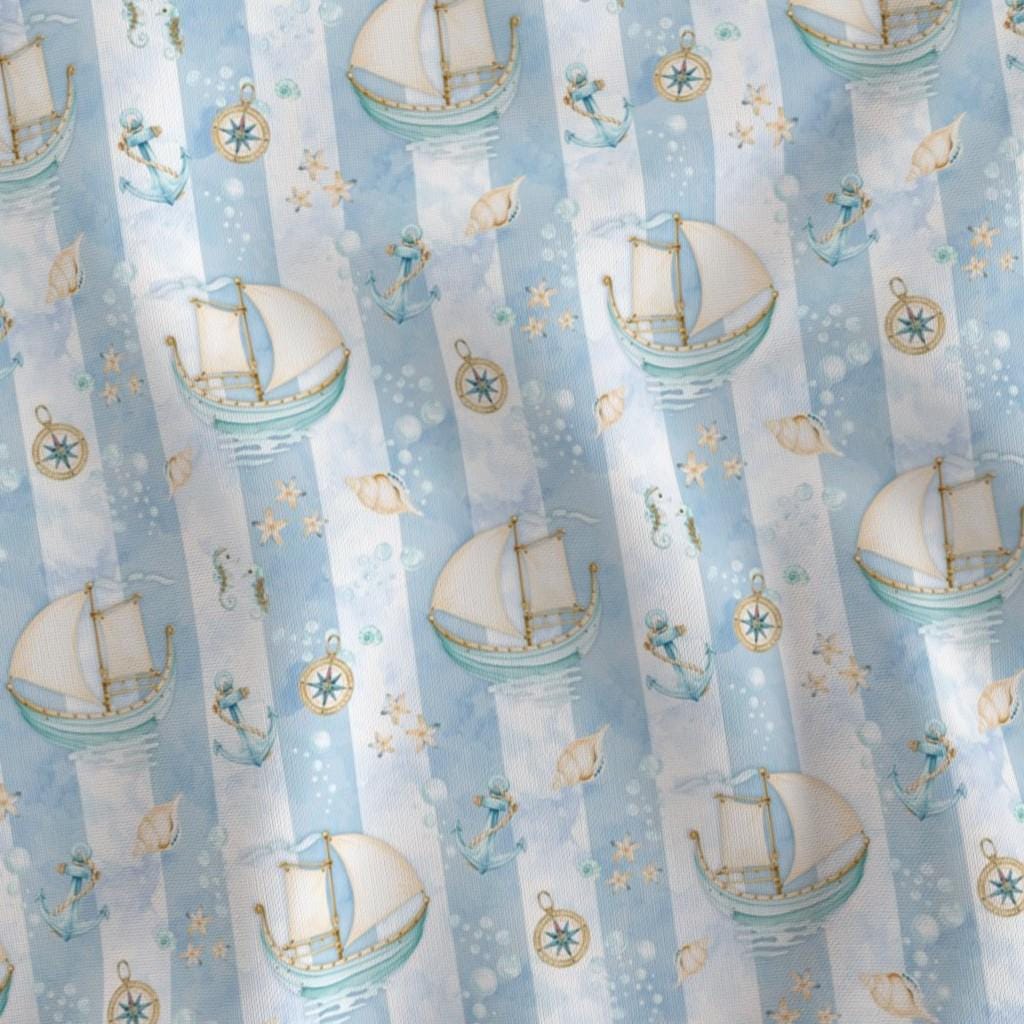 Close-up of Ships Stripe fabric with watercolor sailboats and compass illustrations